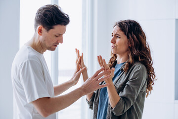 Married curly-haired woman quarrels angrily gesticulating and shouting with brunet husband over...