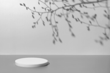 Abstract minimal nature scene - empty stage and white circle podium on gray background and soft plants leaves shadows. Pedestal for cosmetic product and packaging mockups display presentation