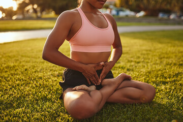 Fit young woman in sportswear meditating in a park - obrazy, fototapety, plakaty