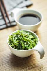 Green wakame. Seaweed salad and soy sauce in bowl.