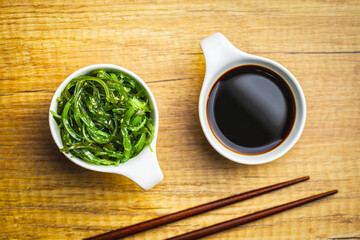 Green wakame. Seaweed salad and soy sauce in bowl.