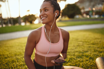 Smiling young woman listening to music after practicing yoga outdoors