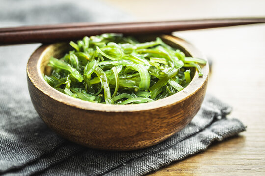 Green wakame. Seaweed salad in bowl on wooden table.