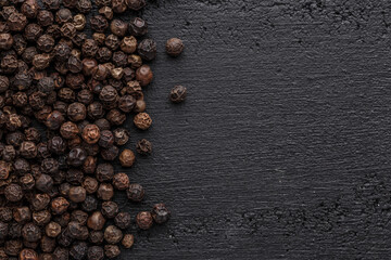 Peppercorn background. Dry black pepper seeds. Top view.On a black background. free space for your text.