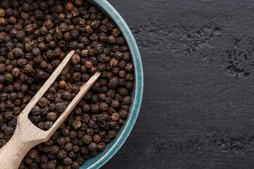Peppercorn background. Dry black pepper seeds. Top view.On a black background. free space for your...