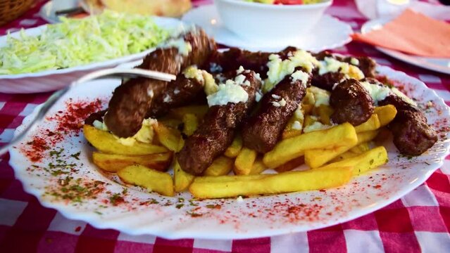 Serbian national dish cevapcici or cevapi (minced meat sausages reminiscent of kebab) along with french fries and salads in the background. The concept of national food.