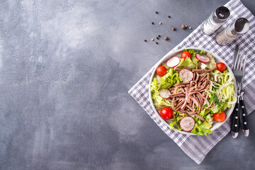 Tasty salad with beef tomgue and vegetables on a plate. Top view, copy space