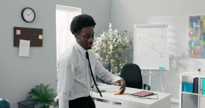 Man with afro dances in the middle of the company office, practicing new moves before the event, happy to win a contract, good news, employee got a promotion, ends work earlier, higher pay