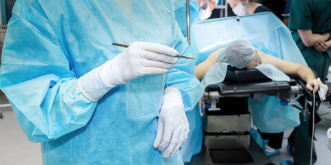 Surgeon with a scalpel in the operating room. Selective focus. A doctor in a blue operating uniform...