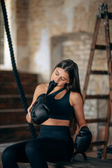 Obraz premium Beautiful young fitness girl taking off a boxing glove