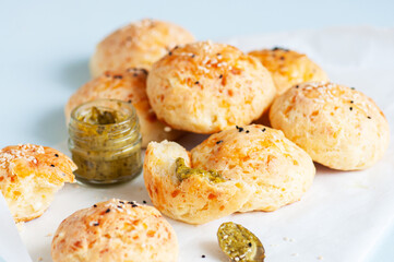 Homemade small cheese dinner rolls with sesame seeds on a baking paper.