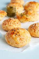 Homemade small cheese dinner rolls with sesame seeds on a baking paper.