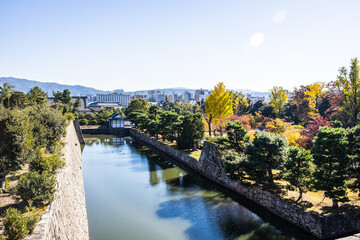 The moat of Nijo Castle with the city of Kyoto in the background and fall colors on the trees in...