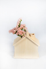 wooden house green energy design represented with pink flowers growing outside of house roof on white background