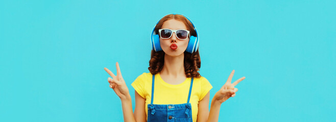 Portrait of young woman listening to music in headphones on colorful blue background