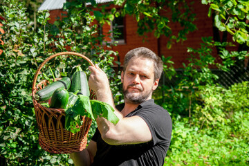 Portrait of a bearded male farmer with a basket full of ripe, fresh vegetables	
