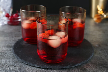 Delicious cocktails with strawberries and ice balls on grey table