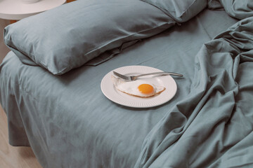 Morning. Tasty healthy breakfast with fried eggs on a beautiful white plate on bed