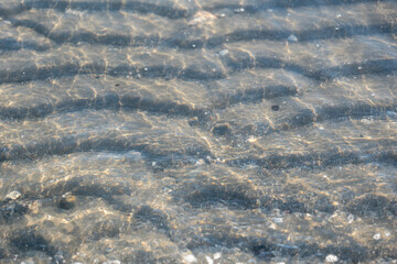 scallops of sand under transparent sea water on the beach