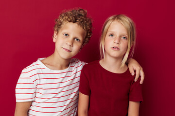 Small children emotions stand side by side in everyday clothes red background unaltered