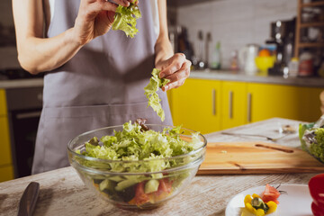 Woman cooking vegetable salad at kitchen. Homemade food and healthy eating concept