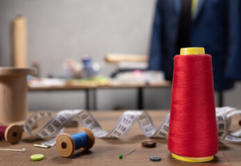 Thread spool and needle with sewing tools on table. Concept of clothes atelier workplace