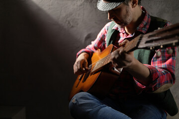 Man playing guitar. Musician in studio with classic acoustic guitar near wall