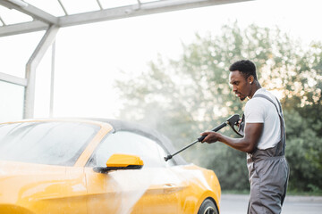 Washing outside rearview car mirror with high pressure water at self car wash service outdoors....