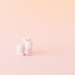 A creative Easter concept made of a pink rabbit on a pink background with copy space. Minimal monochromatic concept. Spring inspiration.