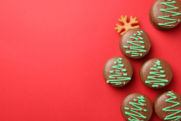 Beautifully decorated Christmas macarons on red background, flat lay. Space for text