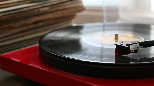  Vinyl Record Spins On A Turntable Playing Music With A Stack Of Vinyl Records In The Background.