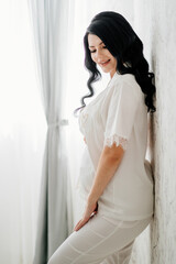 beautiful pregnant bride brunette in white pajamas. 