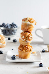 Homemade stack of blueberry muffins on white plate with coffee cup and berries
