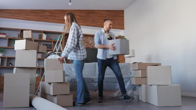 Young couple carrying boxes in new apartment on moving day.New accommodation or rented flat.Happy homeowners portrait on relocation day. Real estate and tenancy concept. Loan mortgage for young family