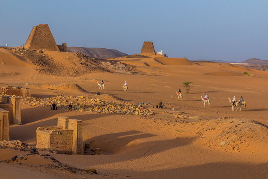 MEROE, SUDAN - MARCH 4, 2019: Locals on camels near Meroe pyramids, Sudan