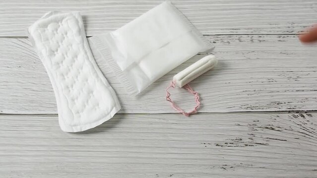 Different types of feminine menstrual hygiene materials products such as pads cloths tampons and cups. White wooden background 