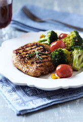 Grilled Turkey Breast with oven baked broccoli, cherry tomatoes and sweet corn. Bright wooden background. Close up.	