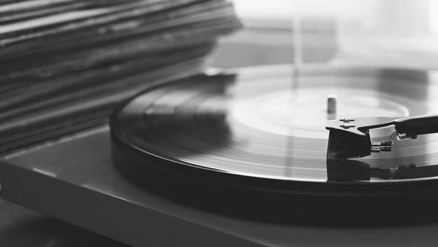 A Vinyl Record Spins On A Turntable Playing Music With A Stack Of Vinyl Records In The Background.