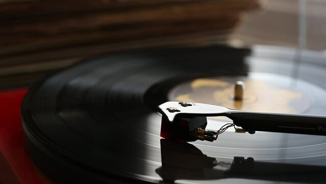 A Vinyl Record Spins On A Turntable Playing Music With A Stack Of Vinyl Records In The Background.