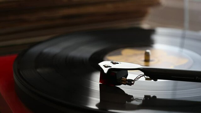 A Vinyl Record Spins On A Turntable Playing Music With A Stack Of Vinyl Records In The Background.