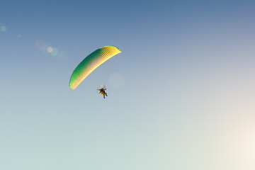 Motorized paraglider flies in the blue sky, extreme sports