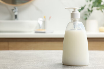 Obraz na płótnie Canvas Dispenser of liquid soap on light grey table in bathroom, space for text