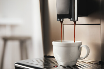 Espresso machine pouring coffee into cup against blurred background, closeup. Space for text