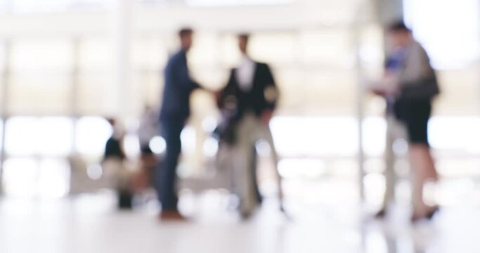 Where businesses come together. Blurred businesspeople in a busy convention centre. Defocused colleagues shaking hands while waiting in an office lobby before a conference meeting