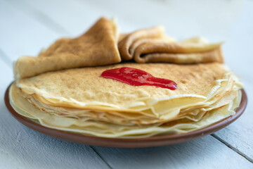 Crepes, thin pancakes on a plate on a white wooden table