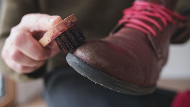 Caucasian Male Polishing Brown Leather Boots Shoes with Soft Brush After Waxing Waterproffing and Impregnating with Shoe Shine Wax