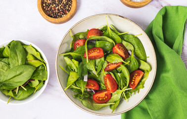 Summer green salad in white bowl plate on grey table