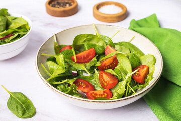 Summer green salad in white bowl plate on grey table