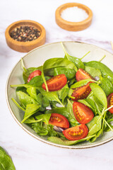 Summer green salad in white bowl plate on grey table