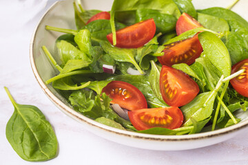Summer green salad in white bowl plate on grey table